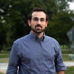 man with dark hair and gotee wearing dark blue gingham dress shirt and glasses