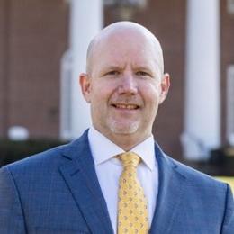 Man in blue sports coat, white dress shirt, and yellow tie